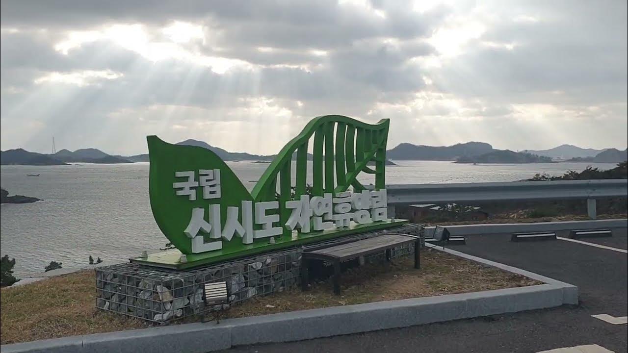 바닷가 배경 앞에 ‘국립신시도자연휴양림’ 표지판이 서 있는 모습